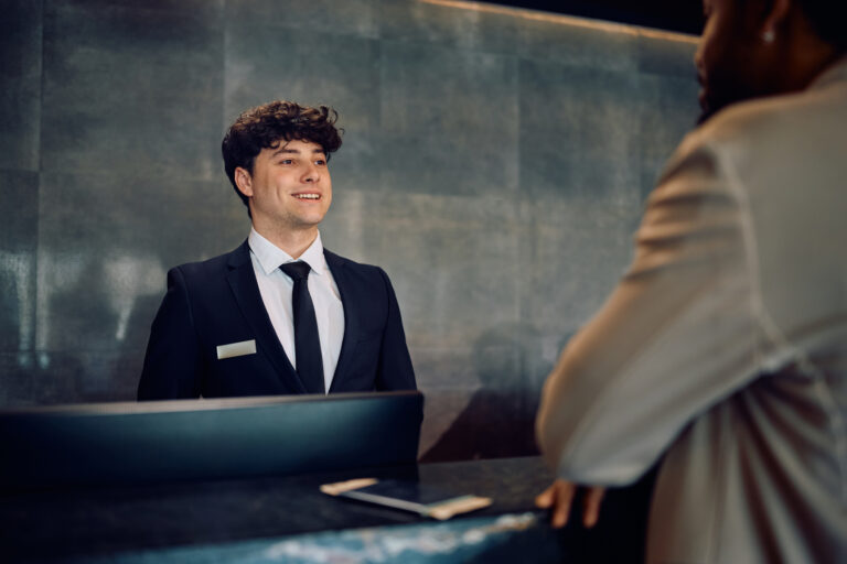 Happy concierge talking to African American man who is checking in at the hotel.