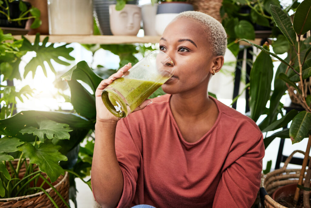 Healthy, black woman and drinking a green smoothie for nutrition with vegetables for supplement. detox and enjoying a vegan drink for home or weightloss with vitamin or plants and fruit shake.