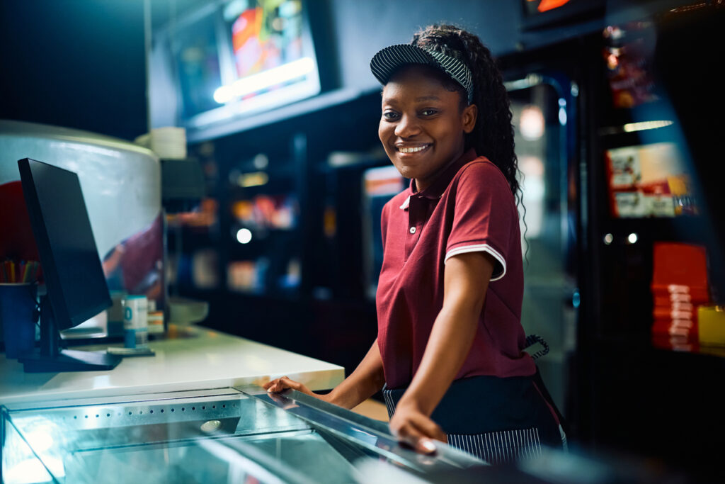 Happy African American concession stand worker in movie theater looking at camera. concessions procurement