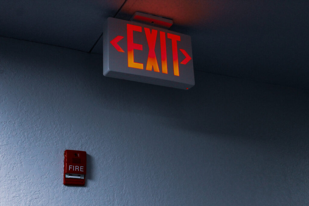 close-up of large illuminated LED emergency exit sign and fire alarm safety pull backdrop