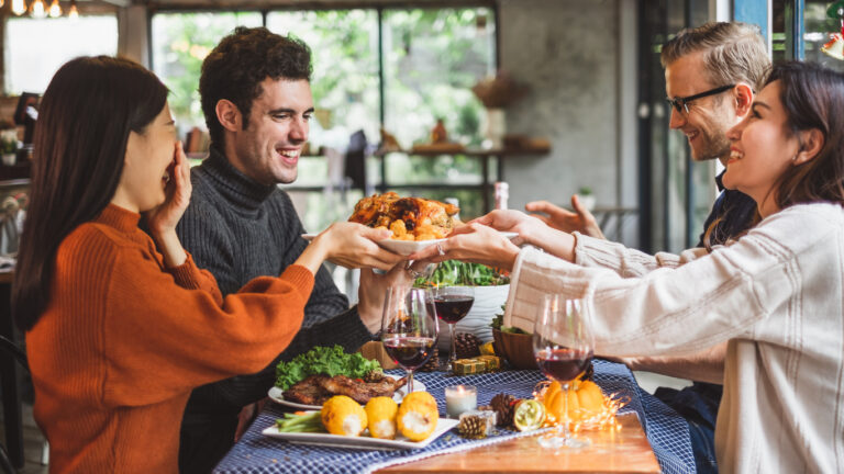 Group of young people celebrating Christmas party dinner with clinking glass of wine