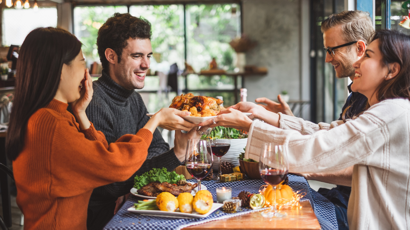 Group of young people celebrating Christmas party dinner with clinking glass of wine