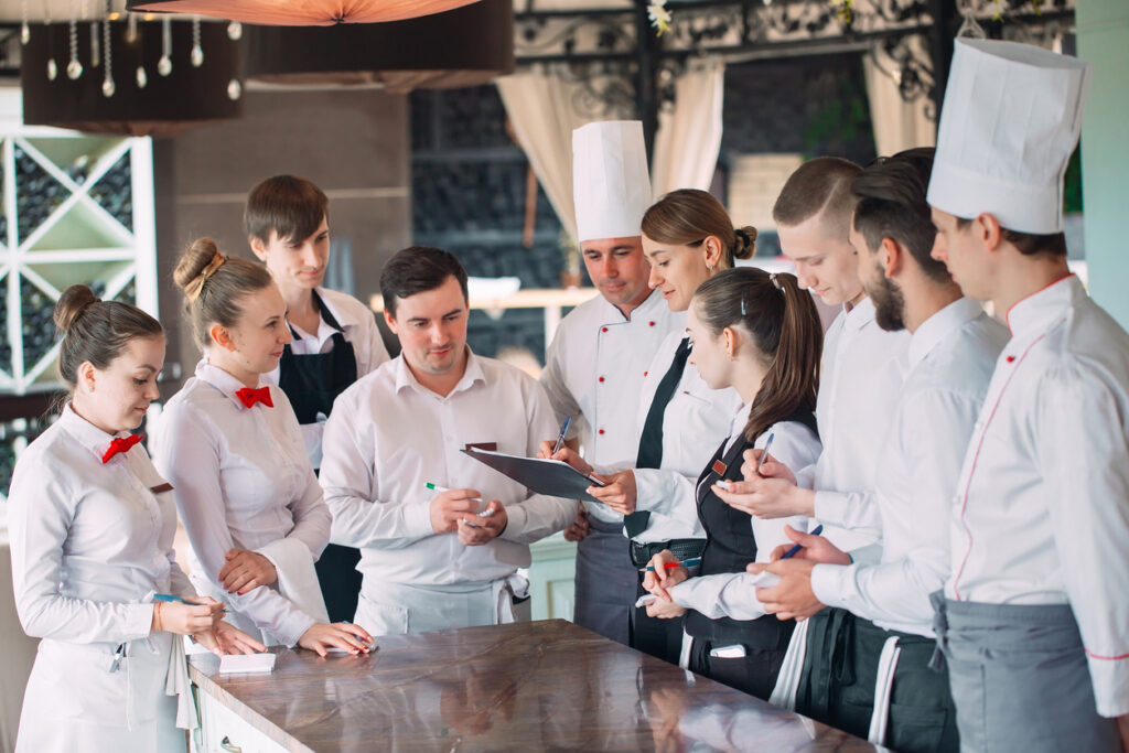 Restaurant manager and his staff in terrace. interacting to head chef in restaurant